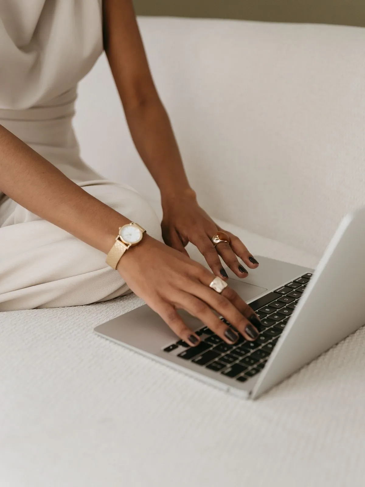 Hands typing on a laptop on a cream sofa